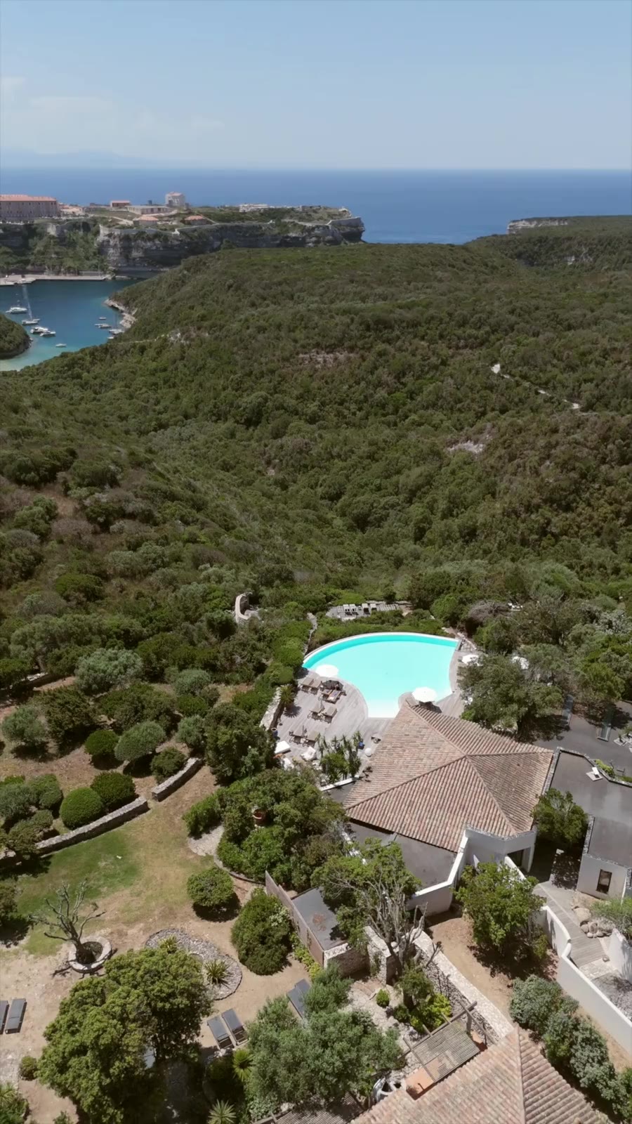 Vue aérienne du domaine de Cala di Greco, piscine et citadelle de Bonifacio en arrière-plan